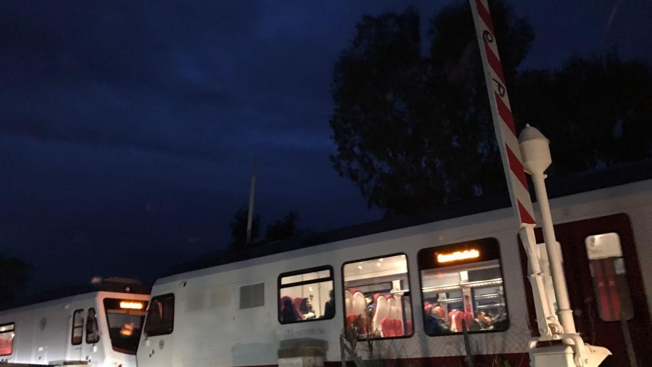 Il treno che transita con il passaggio a livello aperto