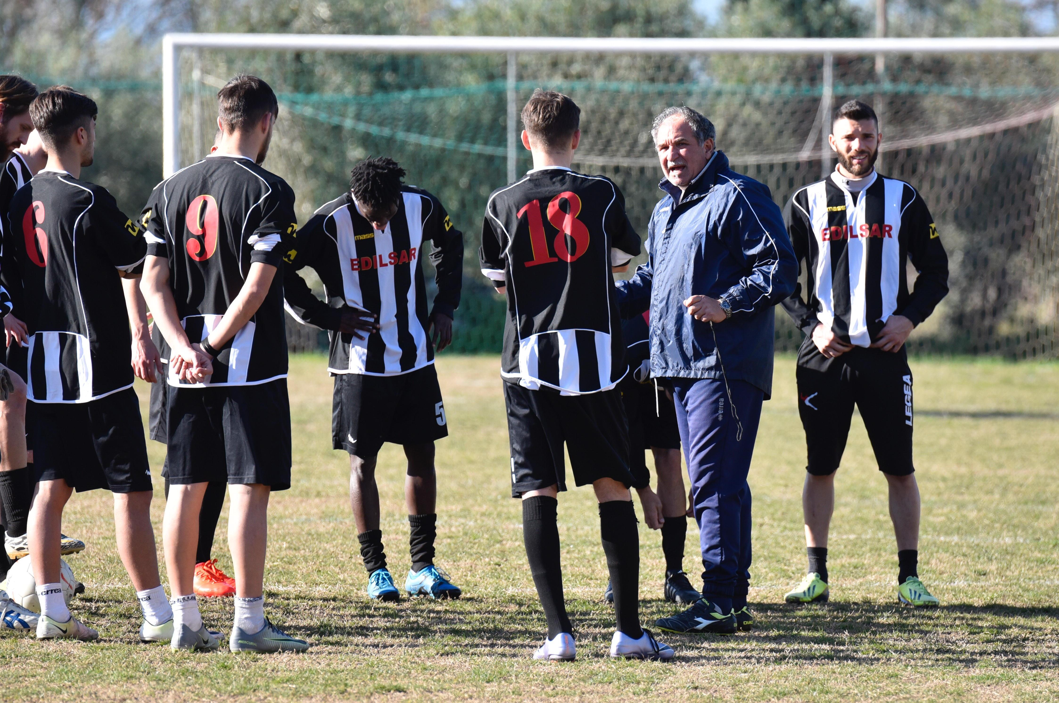 Mister Federici parla con i giocatori del Grosseto (in maglia bianconera) sul campo di Alberese
