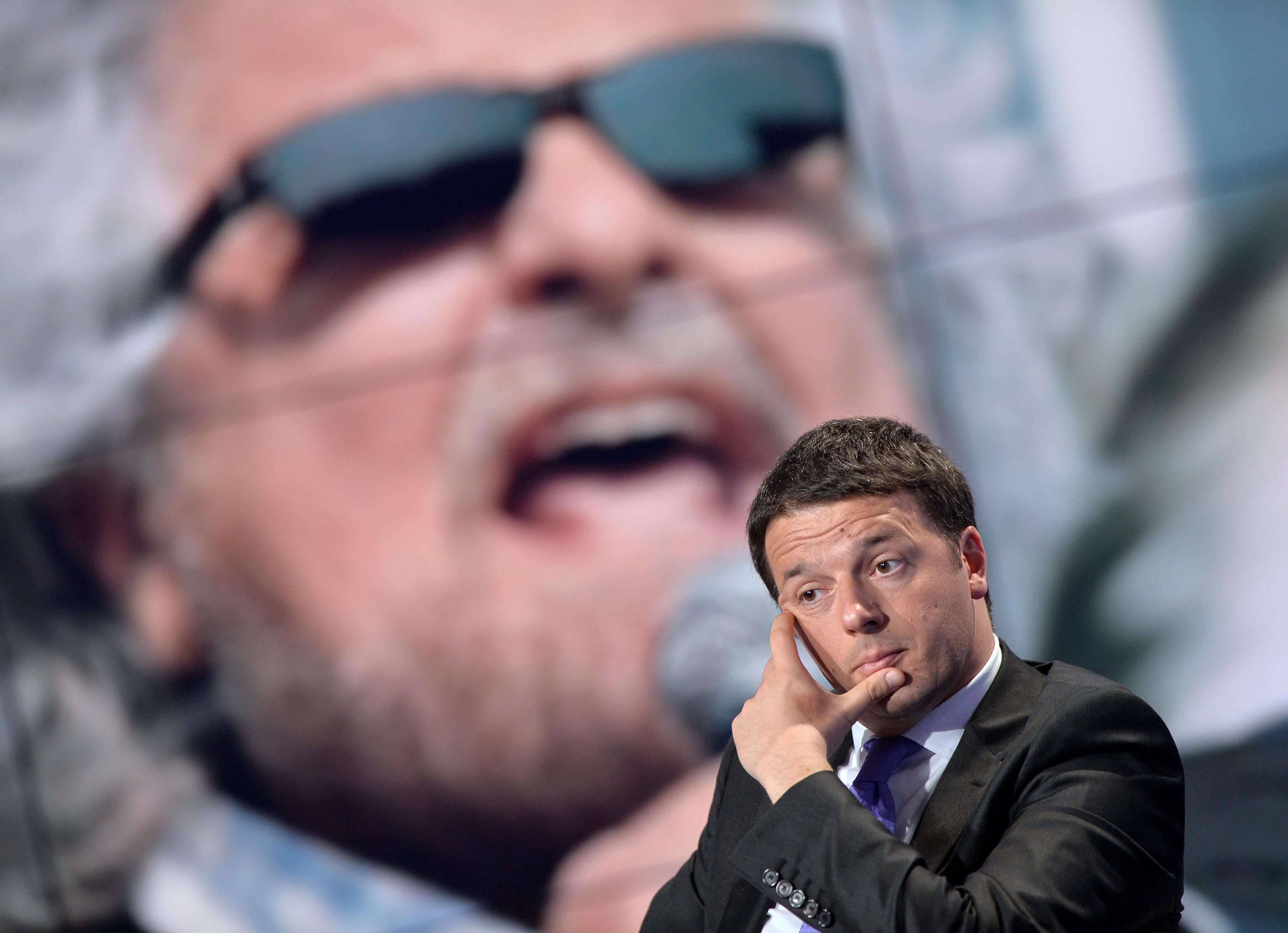 Matteo Renzi e, sullo schermo alle sue spalle, Beppe Grillo