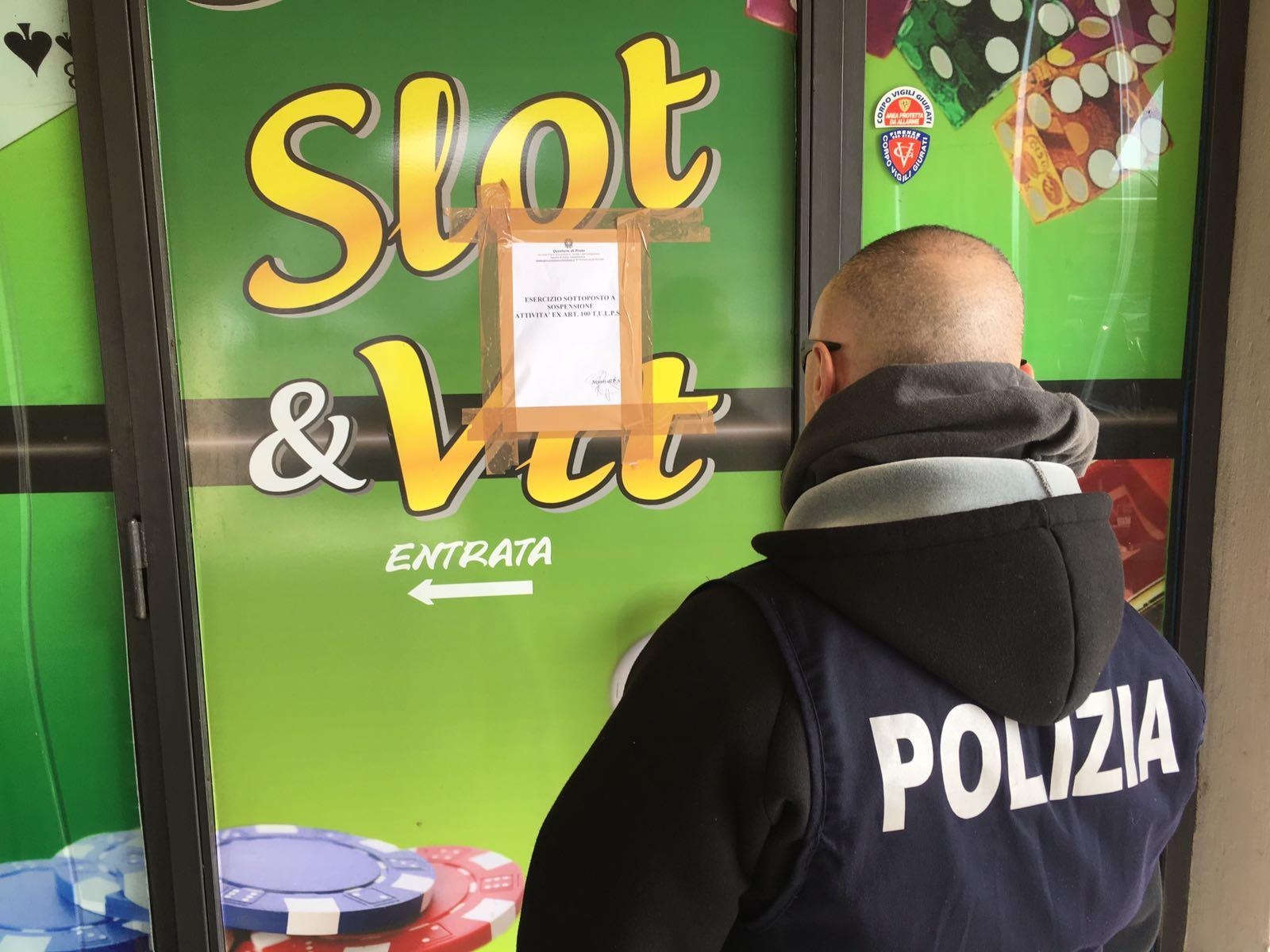 Un poliziotto affigge il provvedimento di sospensione sulla vetrina della sala slot