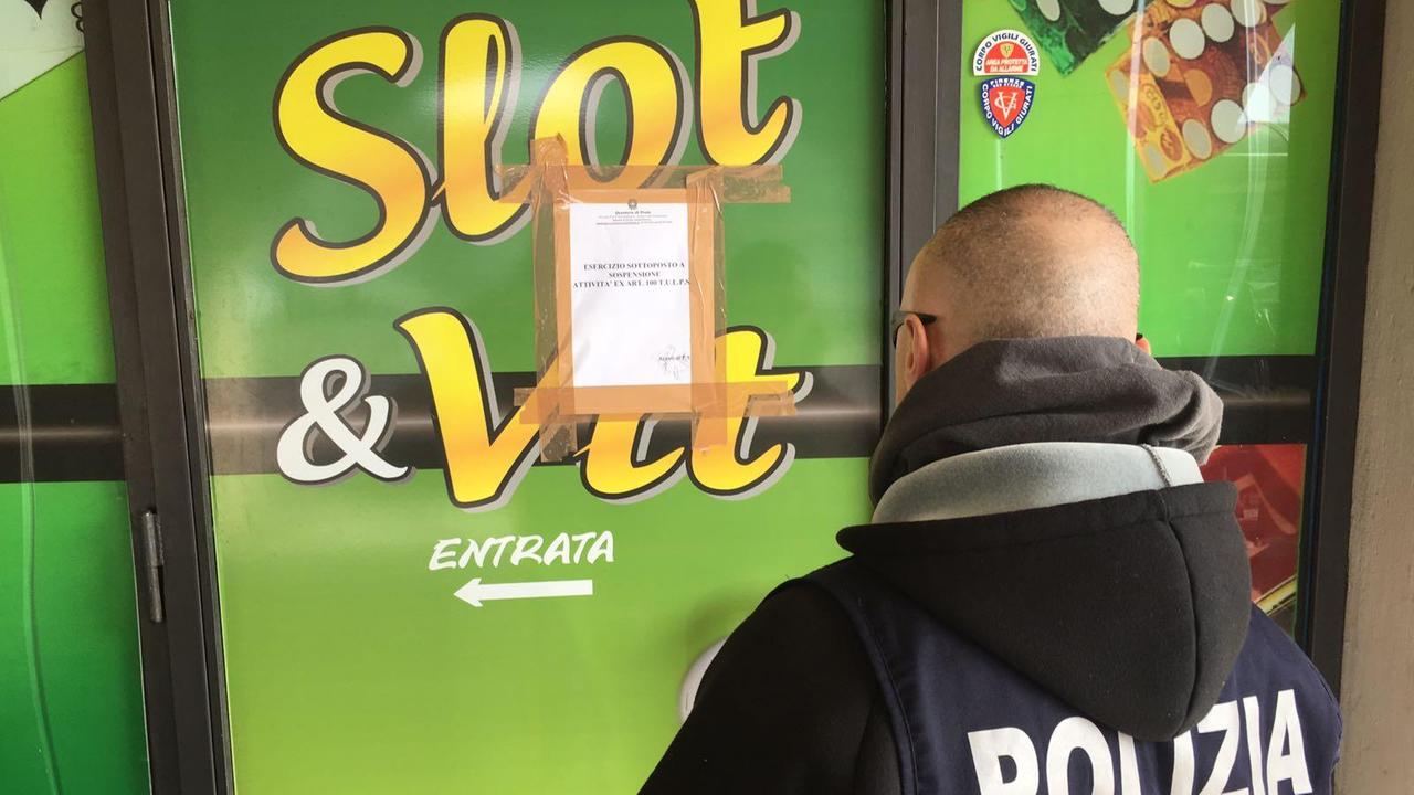 Un poliziotto affigge il provvedimento di sospensione sulla vetrina della sala slot