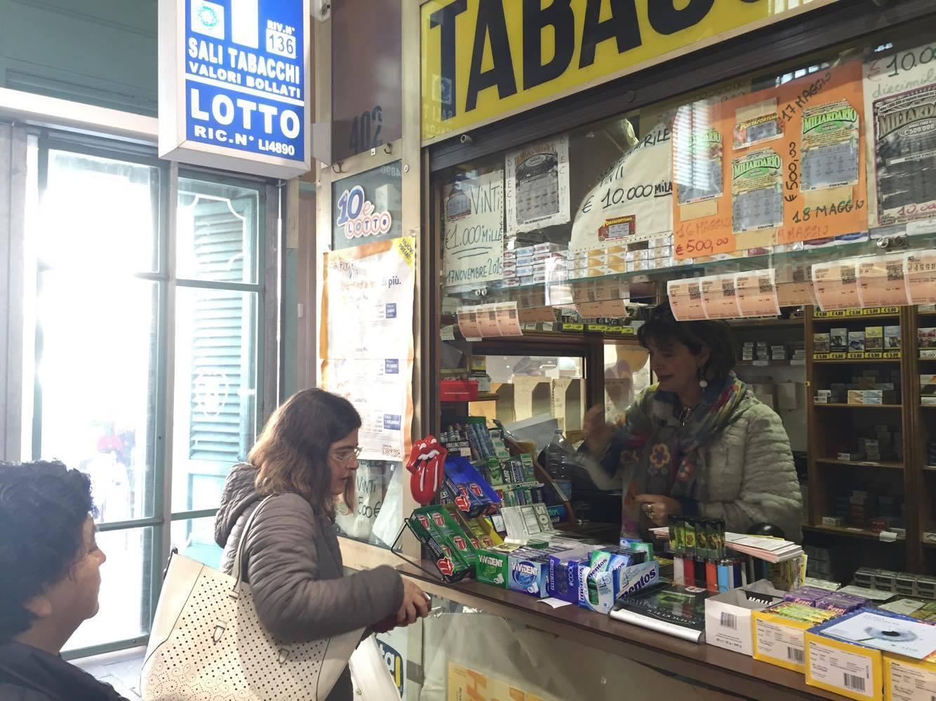 La tabaccaia Cecilia Lombardo serve clienti nel suo chiosco al mercato 