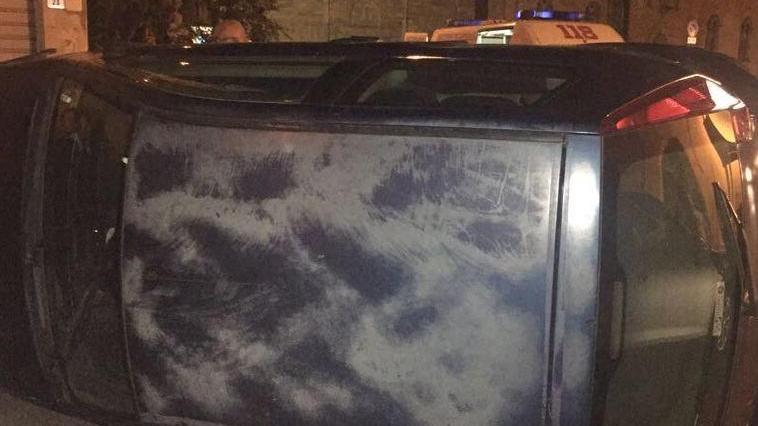 Finisce contro auto in sosta e si ribalta