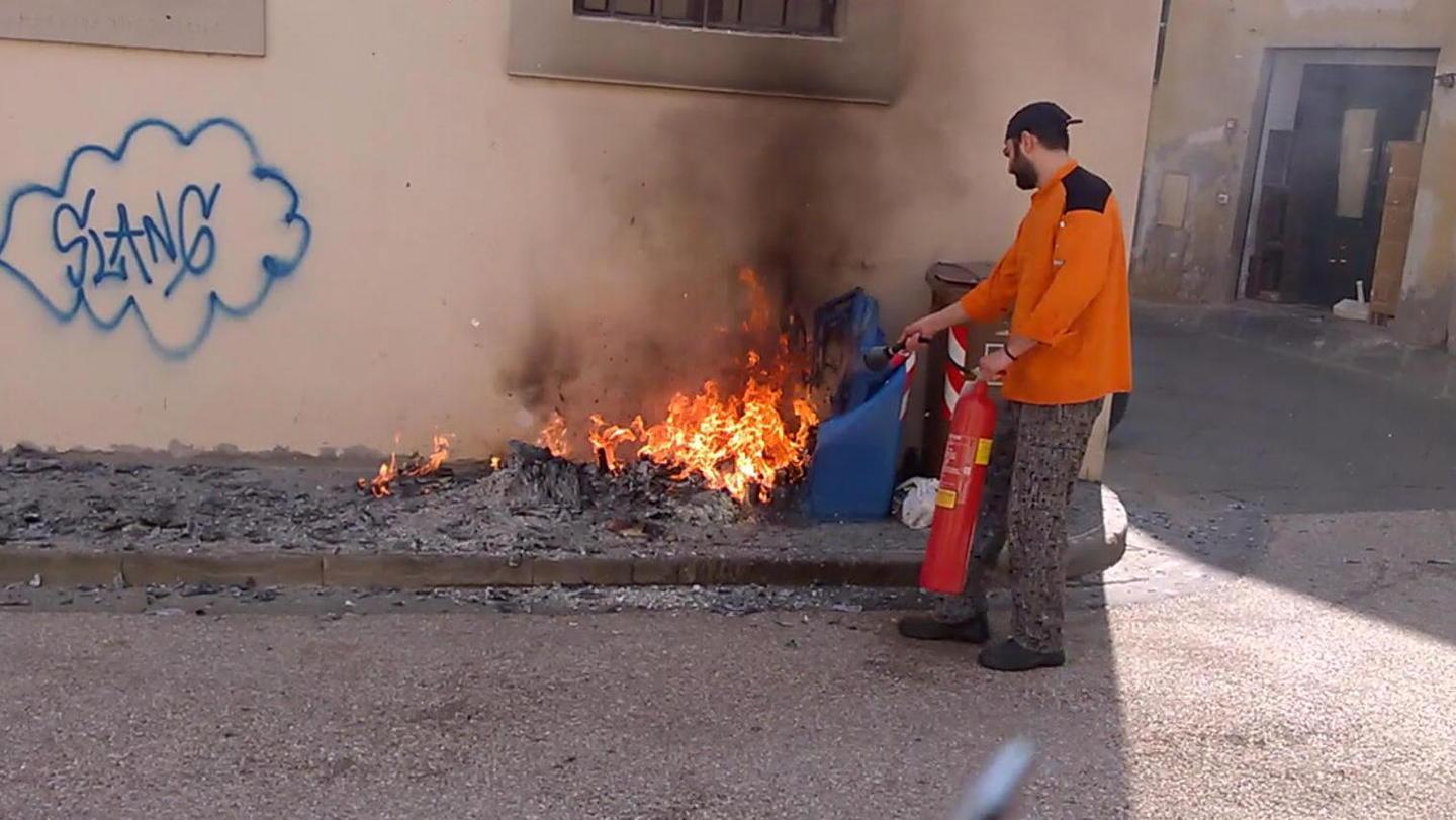 Uno degli addetti del ristorante cerca di spengere i bidoni in fiamme in piazzetta delle Scuole Normali