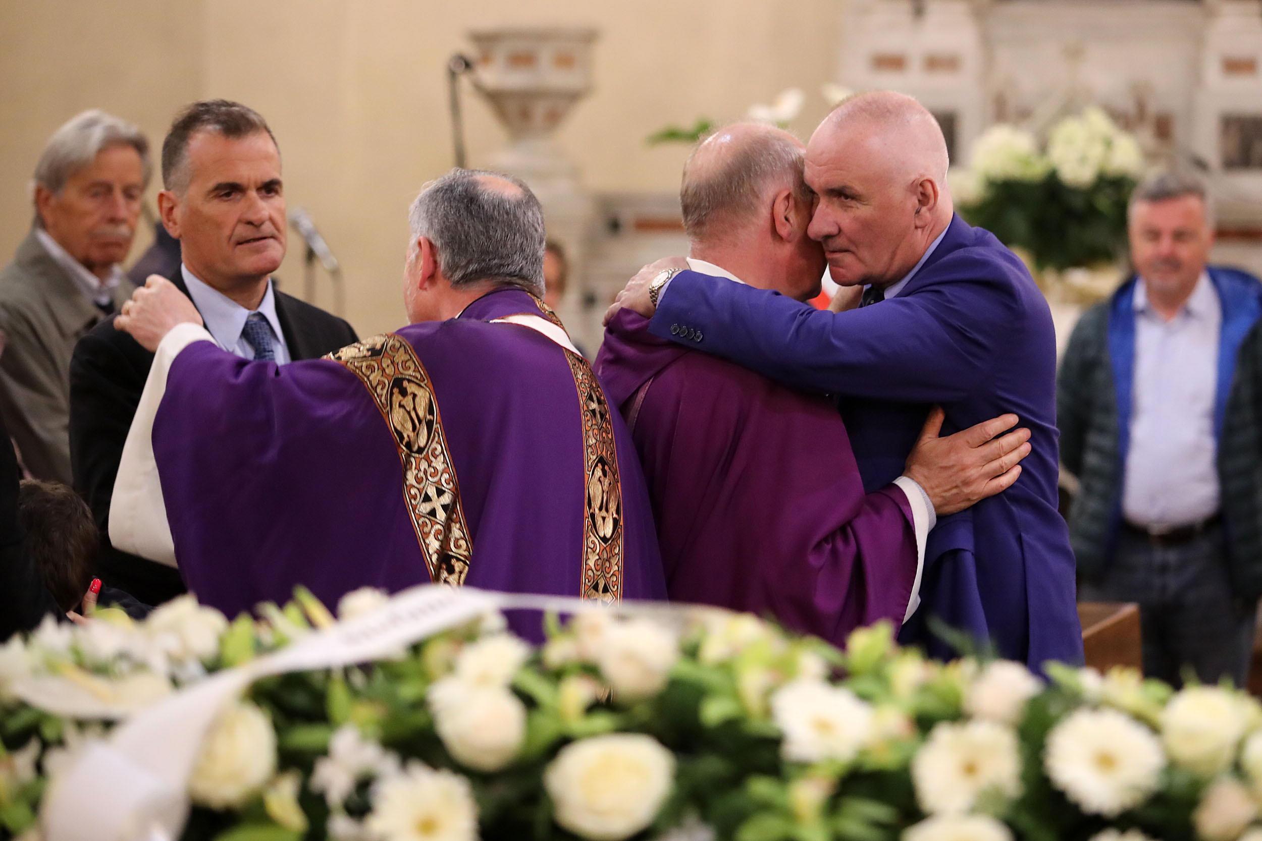 I figli Francesco e Stefano Pucci abbracciano i parroci concelebranti (Foto Nucci)