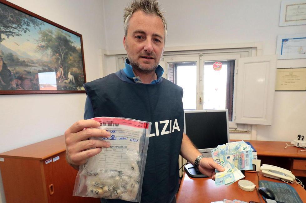 Un poliziotto mostra ovuli e soldi sequestrati ai due nigeriani (Foto Agenzia Carlo Sestini)