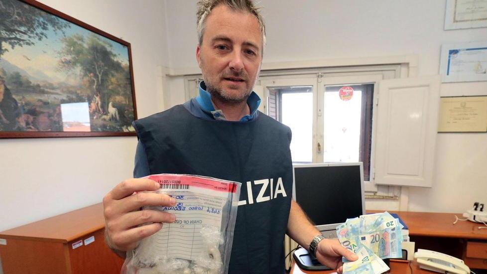 Un poliziotto mostra ovuli e soldi sequestrati ai due nigeriani (Foto Agenzia Carlo Sestini)
