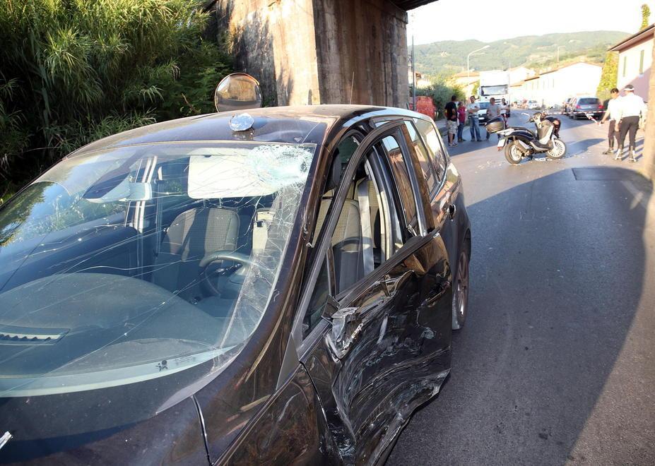 I danni sulla Renault dopo lo scontro e, dietro, lo scooter coinvolto nell’incidente (Foto Paolo Nucci)