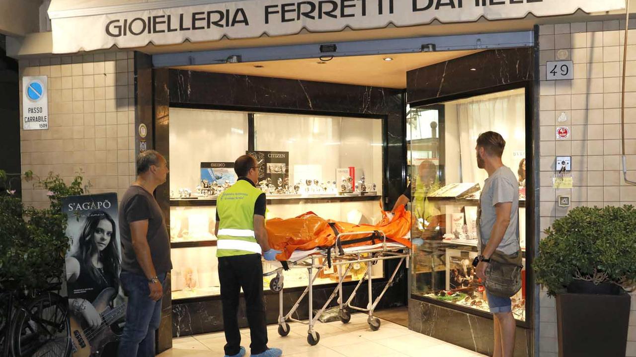 Il cadavere del rapinatore viene portato via dalla gioielleria