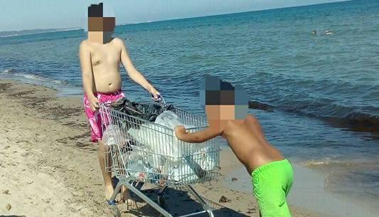 Due ragazzi riempiono il carrello con i rifiuti raccolti a Platamona 