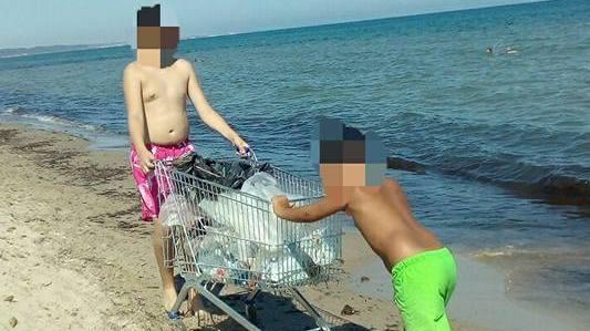 Due ragazzi riempiono il carrello con i rifiuti raccolti a Platamona 