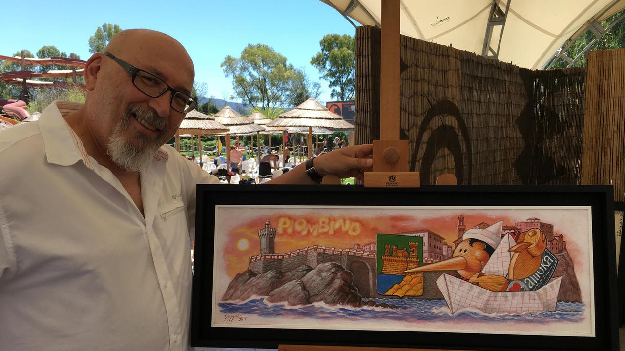 Il pittore Giuliano Giuggioli con la sua opera raffigurante Piombino, l'immagine che da agosto sarà sulle bustine di zucchero del caffè Damoka
