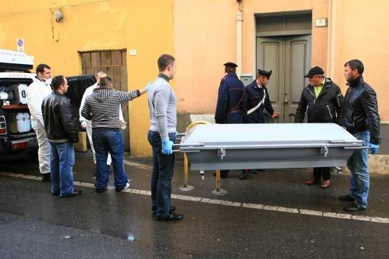 Gli investigatori portano via la salma dalla casa di via Eleonora d'Arborea