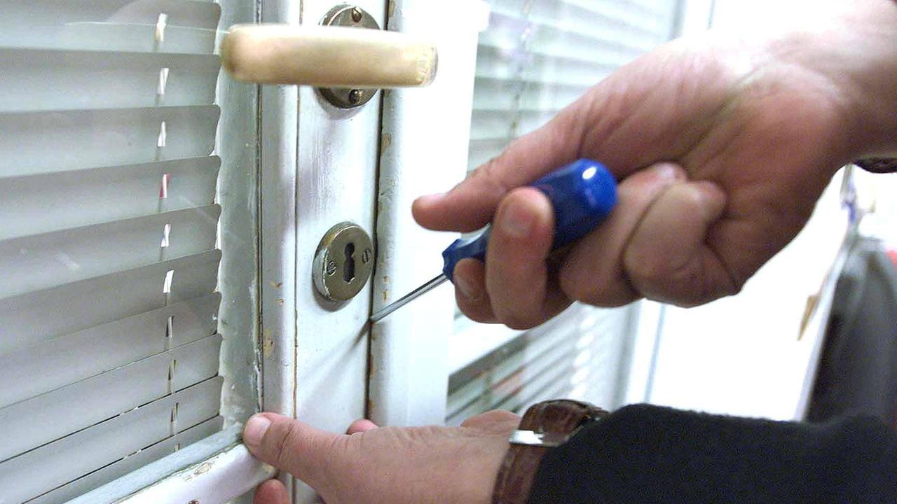 Un ladro scassina una porta (foto di archivio)