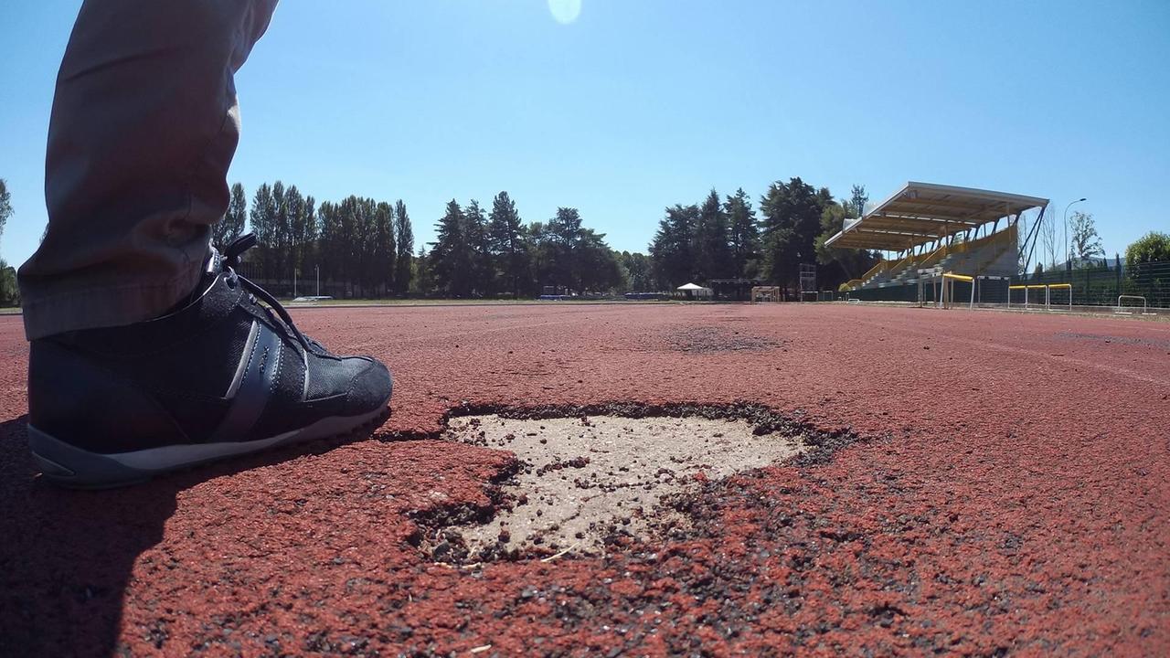 Uno dei punti in cui ll tartan rosso danneggiato lascia spazio alle buche dove spunta il cemento