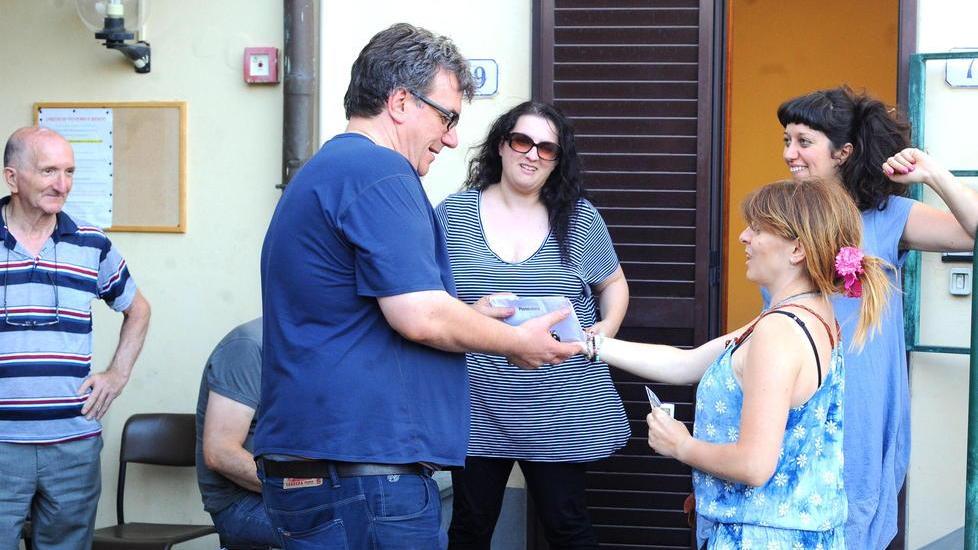 Don Biancalani riceve le offerte raccolte da Francesca Matteoni e NIlo Benedetti per pagare la multa (Foto Gori)