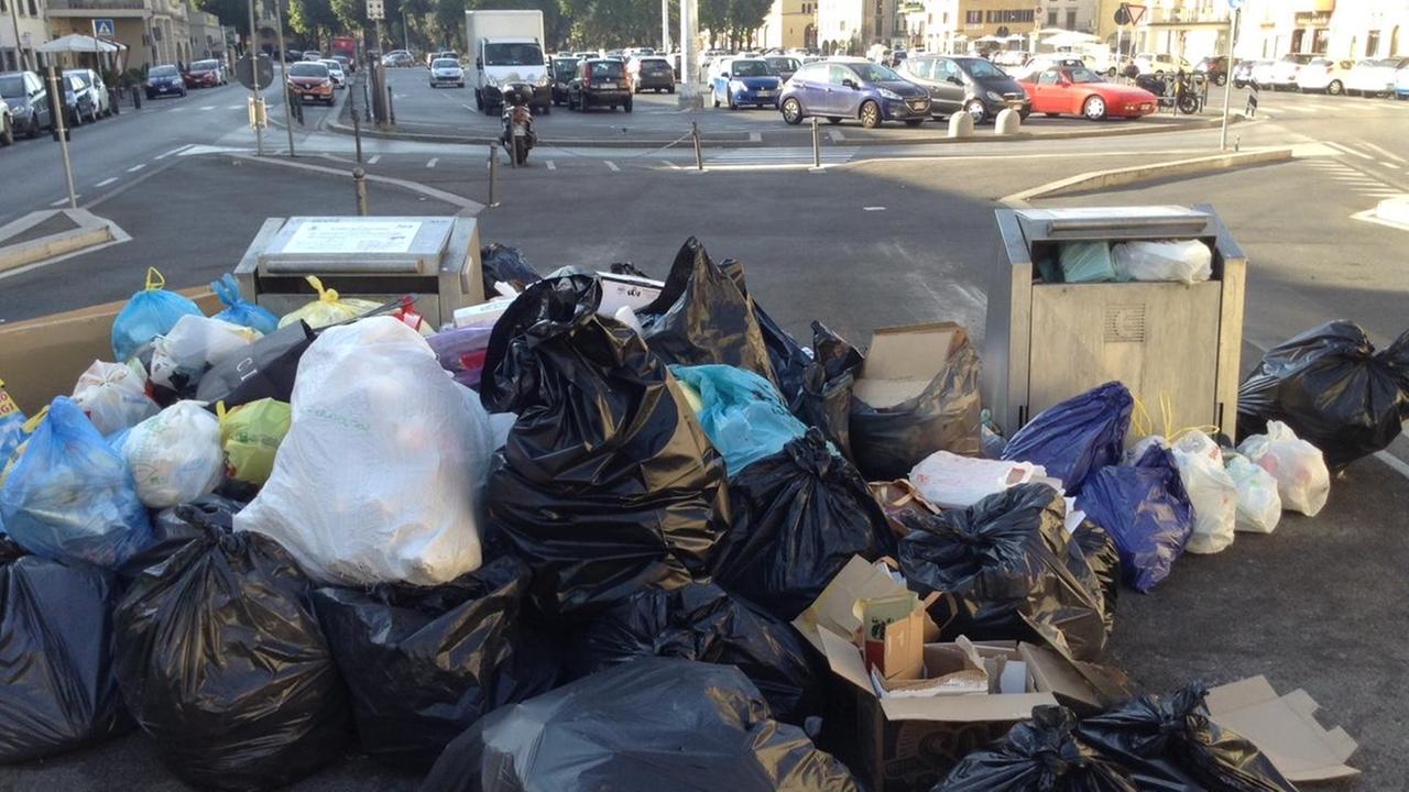 I sacchi di rifiuti intorno all'isola ecologica la mattina di domenica 6 agosto in piazza Mercatale (foto Batavia)
