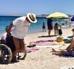 L'uomo trascina in spiaggia la carrozzina con la moglie