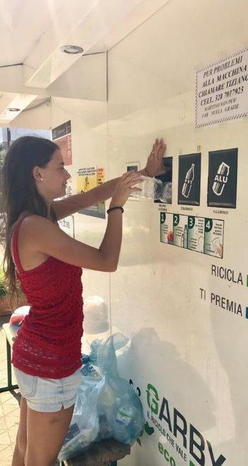 Una ragazza mentre usa la macchina per il riciclo dei rifiuti
