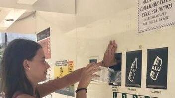 Una ragazza mentre usa la macchina per il riciclo dei rifiuti