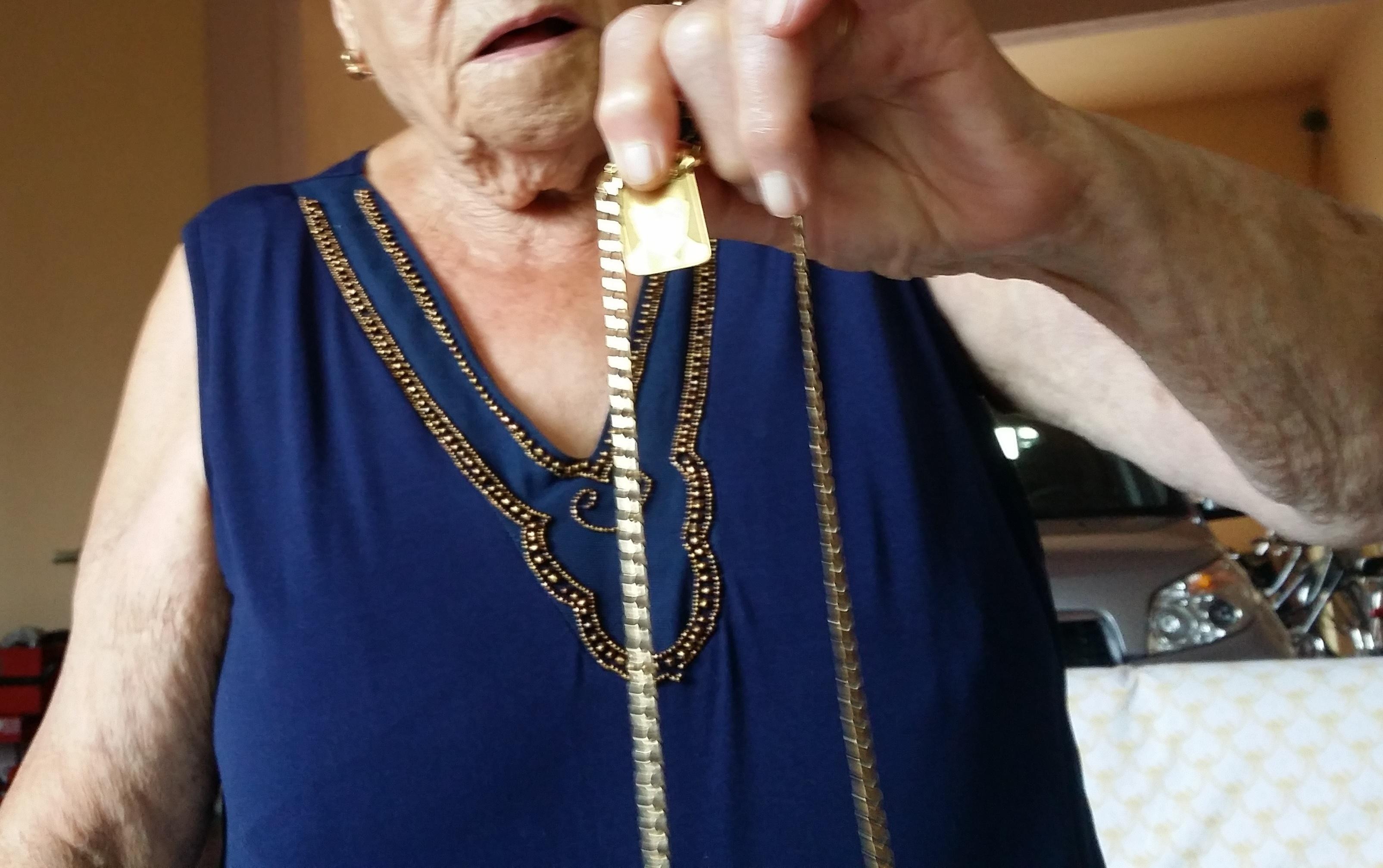 Un'anziana mostra la collana che è riuscita a difendere