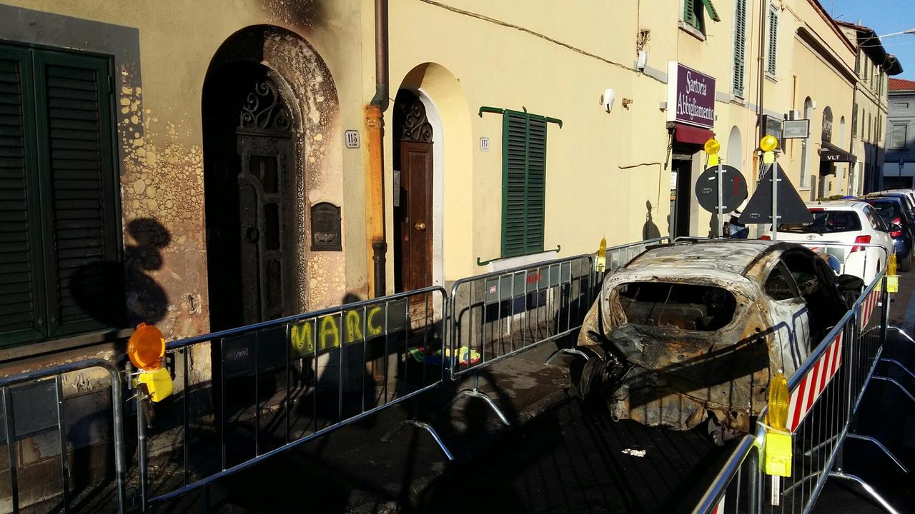 L'auto bruciata in via Pomeria e il portone annerito