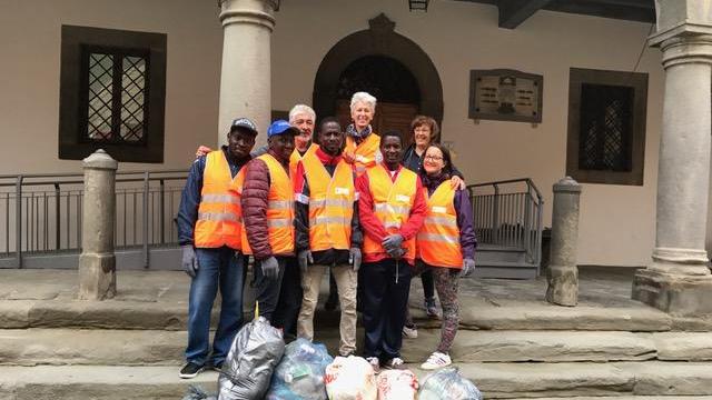 I migranti sulle scale del municipio con i rifiuti raccolti