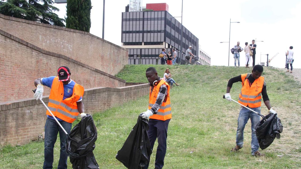 I richiedenti asilo impegnati nella pulizia di un giardino (foto Batavia)