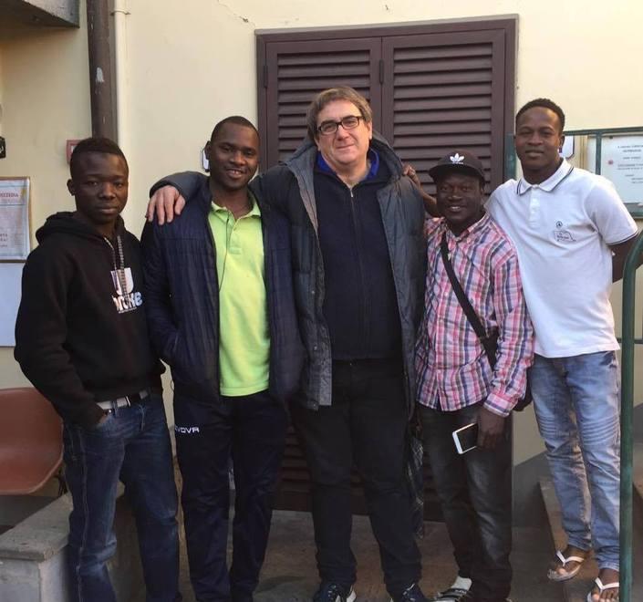 Don Massimo Biancalani con un gruppo di migranti