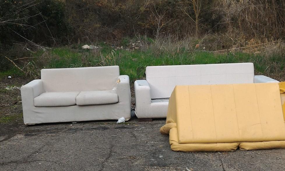 Tre divani scaricati in una stradina 