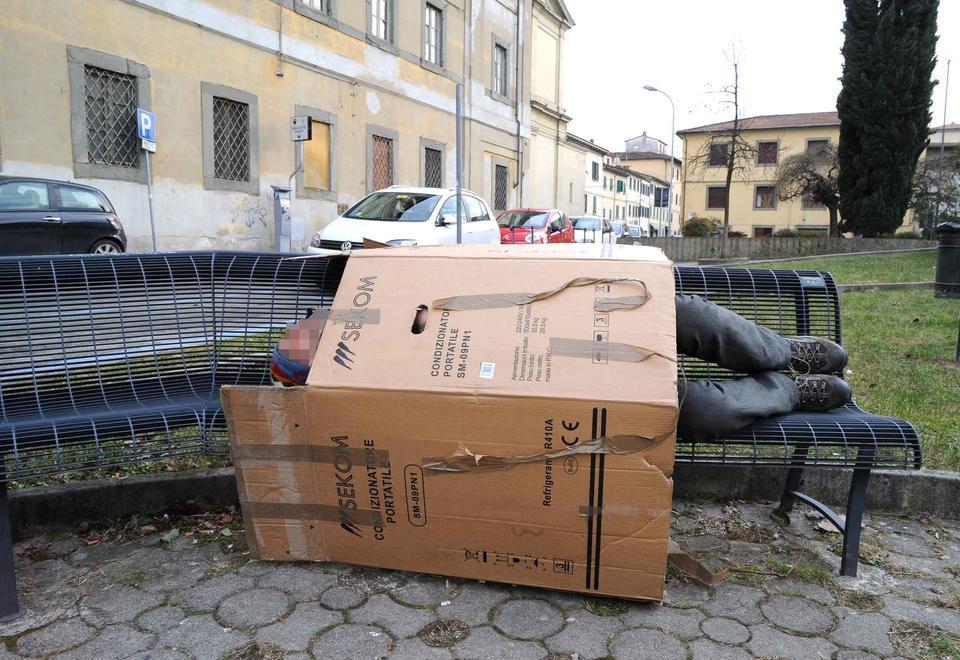 Un senzatetto dorme su una panchina