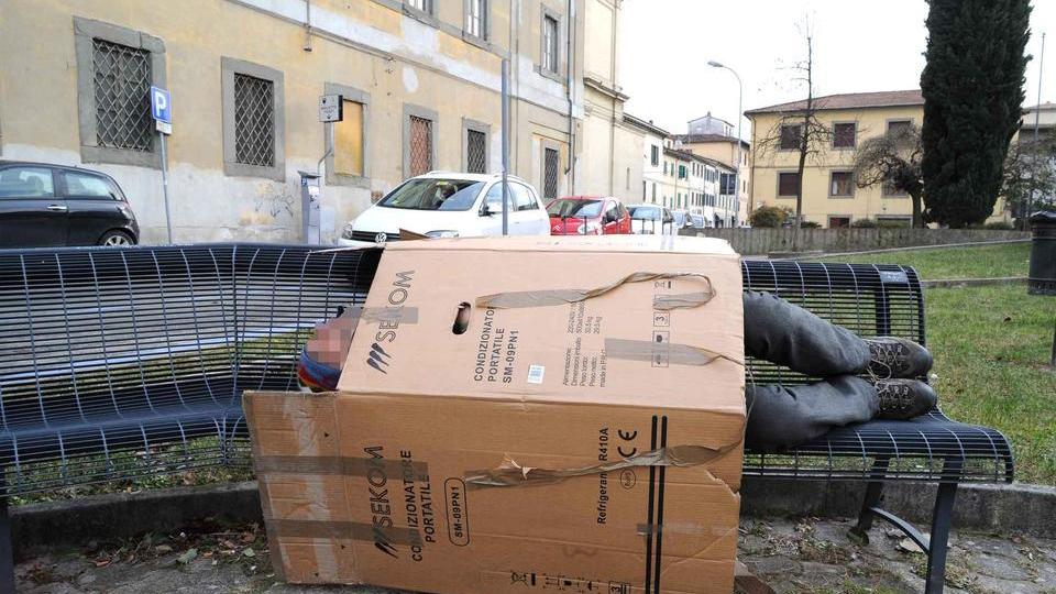 Un senzatetto dorme su una panchina