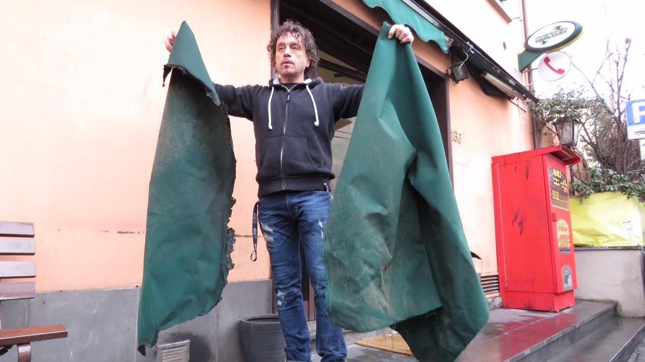 Il titolare del bar Lo Scalino mostra i danni alle tende (foto Batavia)
