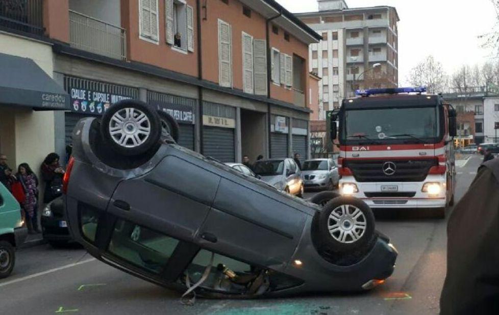 Centra un'auto in sosta e si capovolge in strada