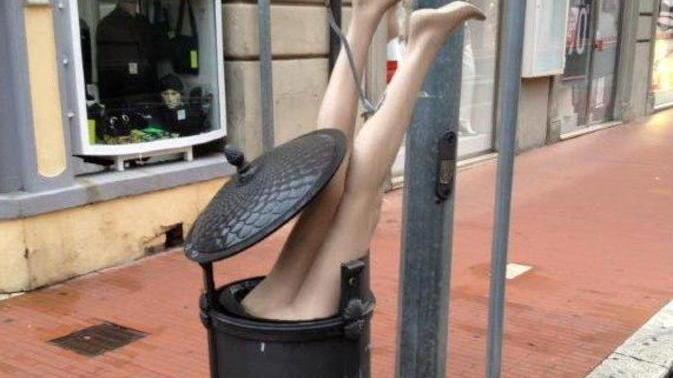 L’immagine delle gambe del manichino che spuntano dal cestino