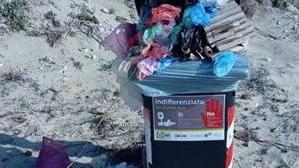 Cestini pieni sulla spiaggia e sporco lasciato per terra