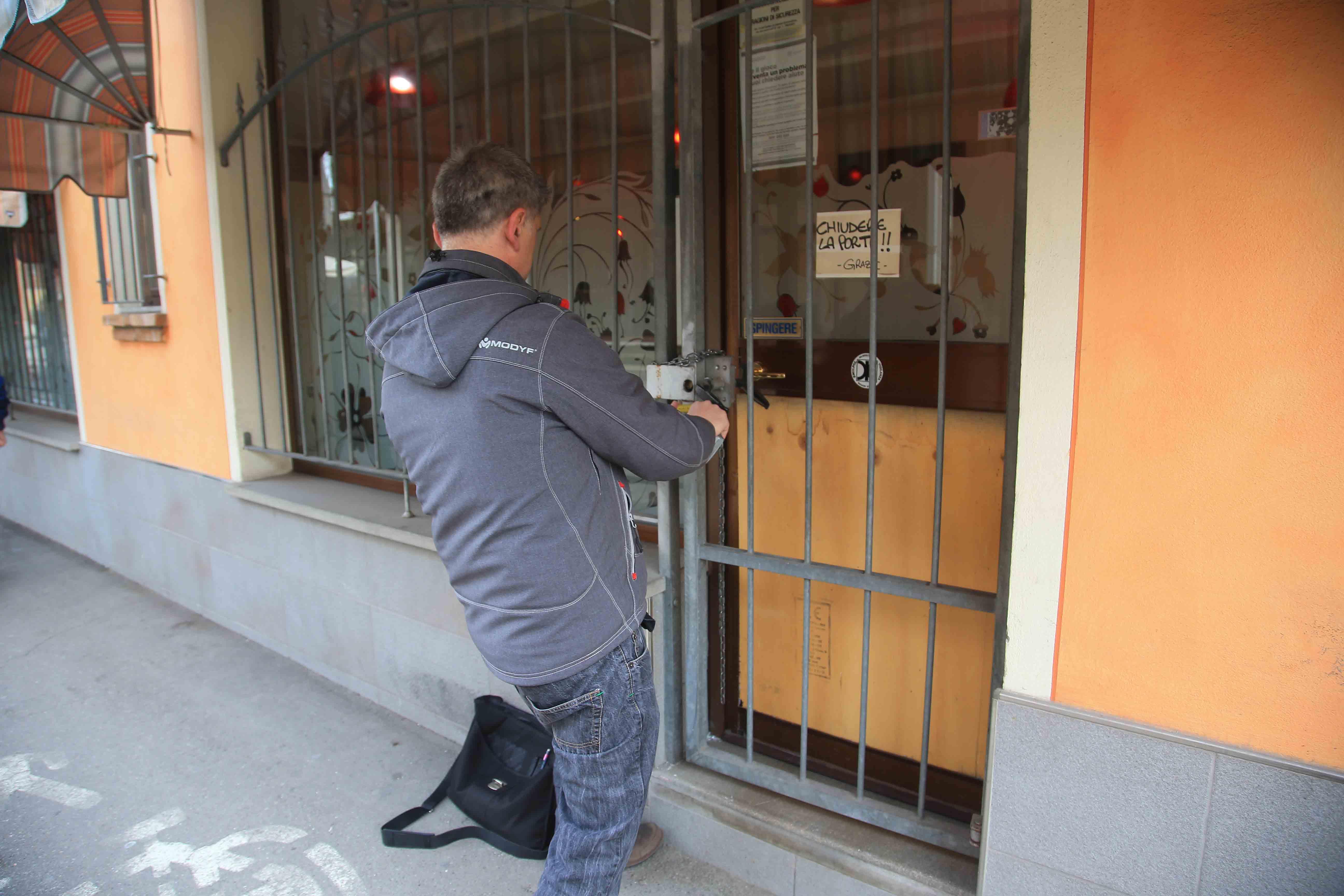 Il vetro infranto della porta d'ingresso del bar di Arceto coperto con un foglio di compensato (foto Santandrea)  