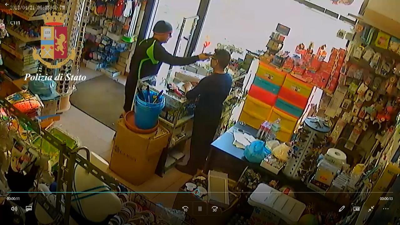 Il rapinatore in azione nel negozio del commerciante cinese