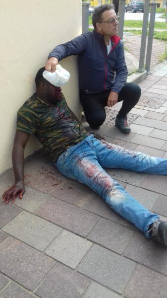 Un passante tampona la ferita al nigeriano ferito