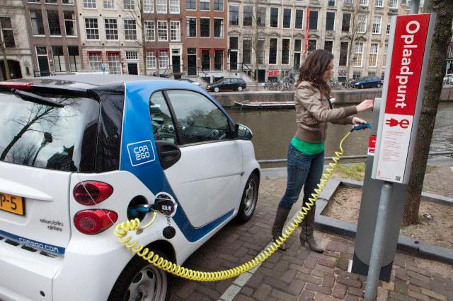Un'automobilista ricarica un'auto elettrica