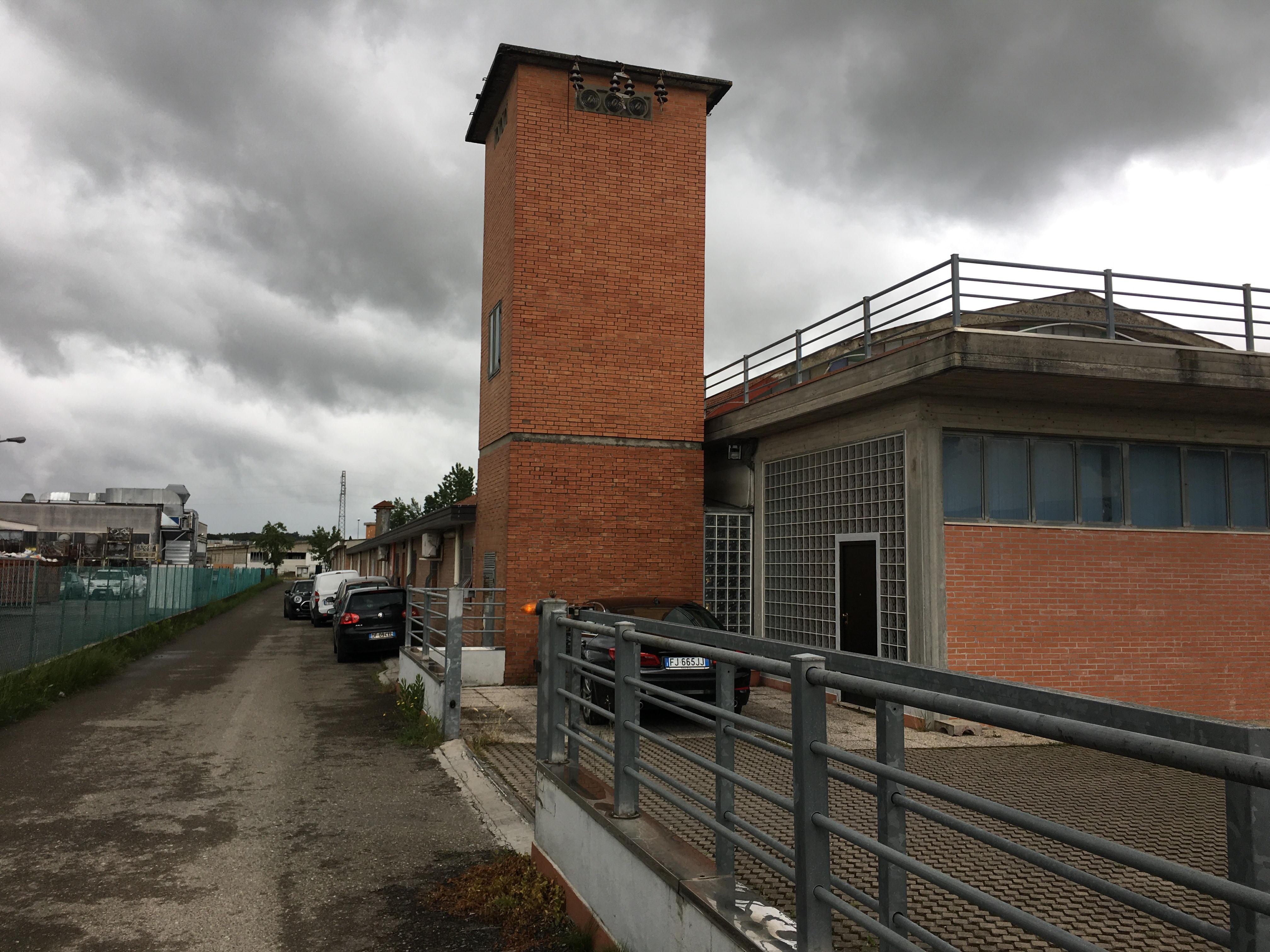 La strada dove ha sede l’azienda presa di mira dai banditi, a destra il logo della ditta (Foto Silvi)