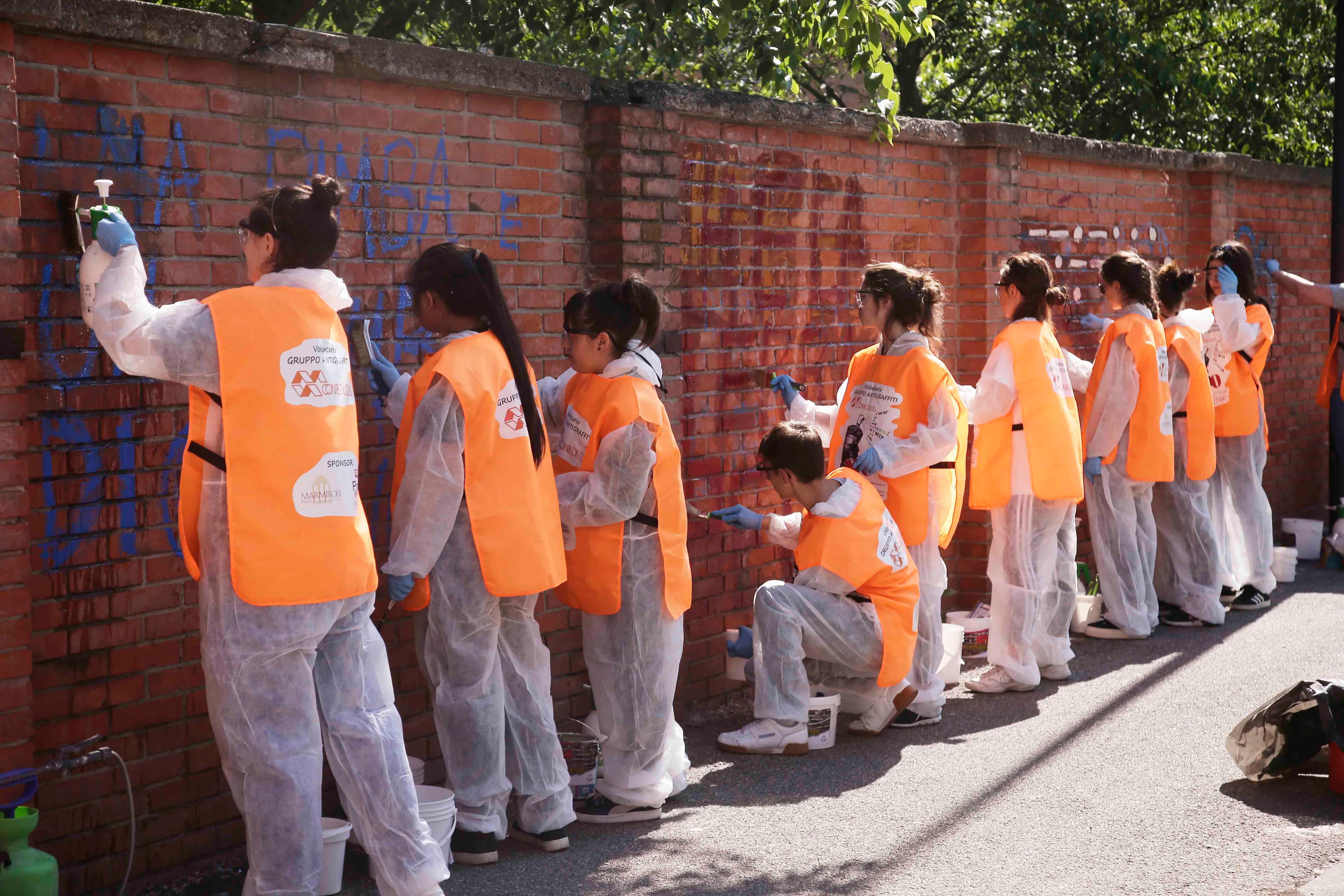 I volontari antigraffiti ripuliscono i muri della scuola materna Lari 