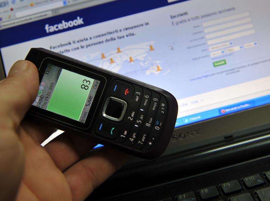 Un cellulare e, sul computer, l'homepage di Facebook