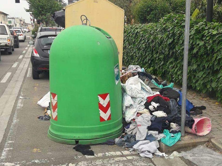 Gli abiti usati abbandonati accanto al cassonetto in via Battisti
