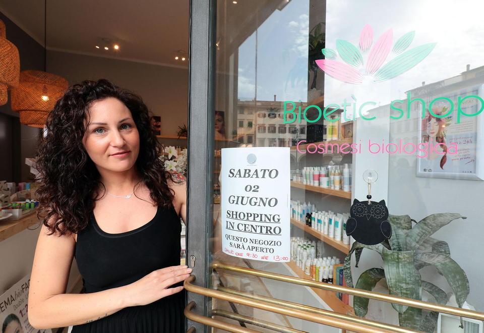 Una commerciante del centro con il cartello di apertura (foto agenzia Sestini)