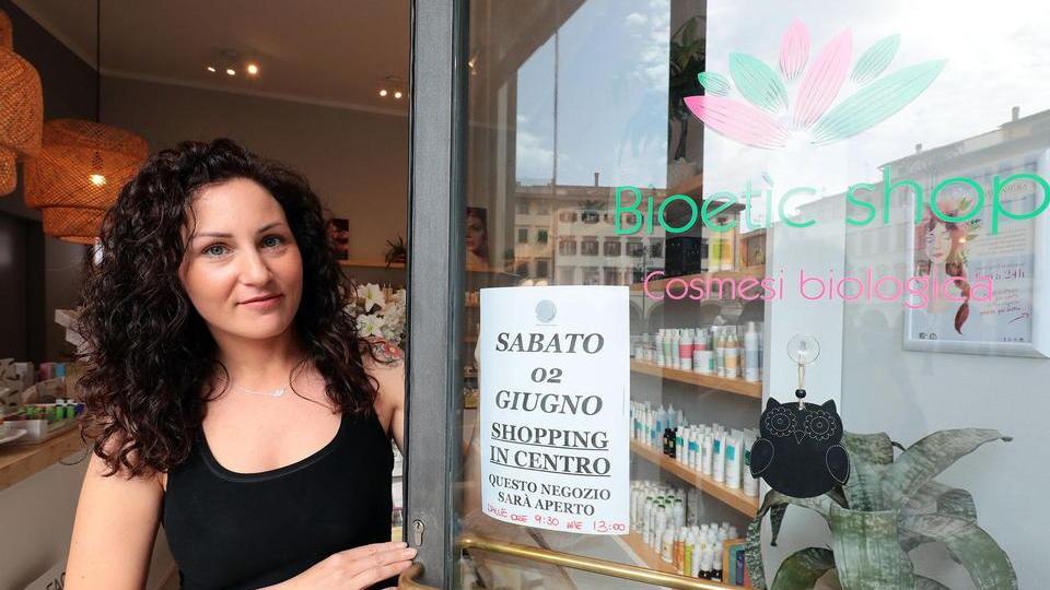 Una commerciante del centro con il cartello di apertura (foto agenzia Sestini)