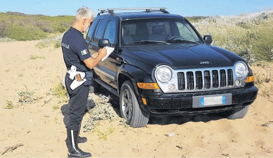 Un vigile urbano davanti al Suv parcheggiato sulla sabbia a Porto Ferro