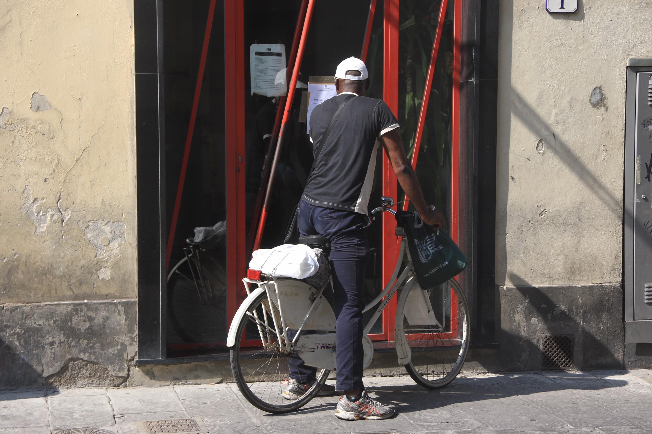 Un uomo in bici mentre legge il cartello di chiusura su uno degli ingressi del bar (foto Sproviero/Batavia)