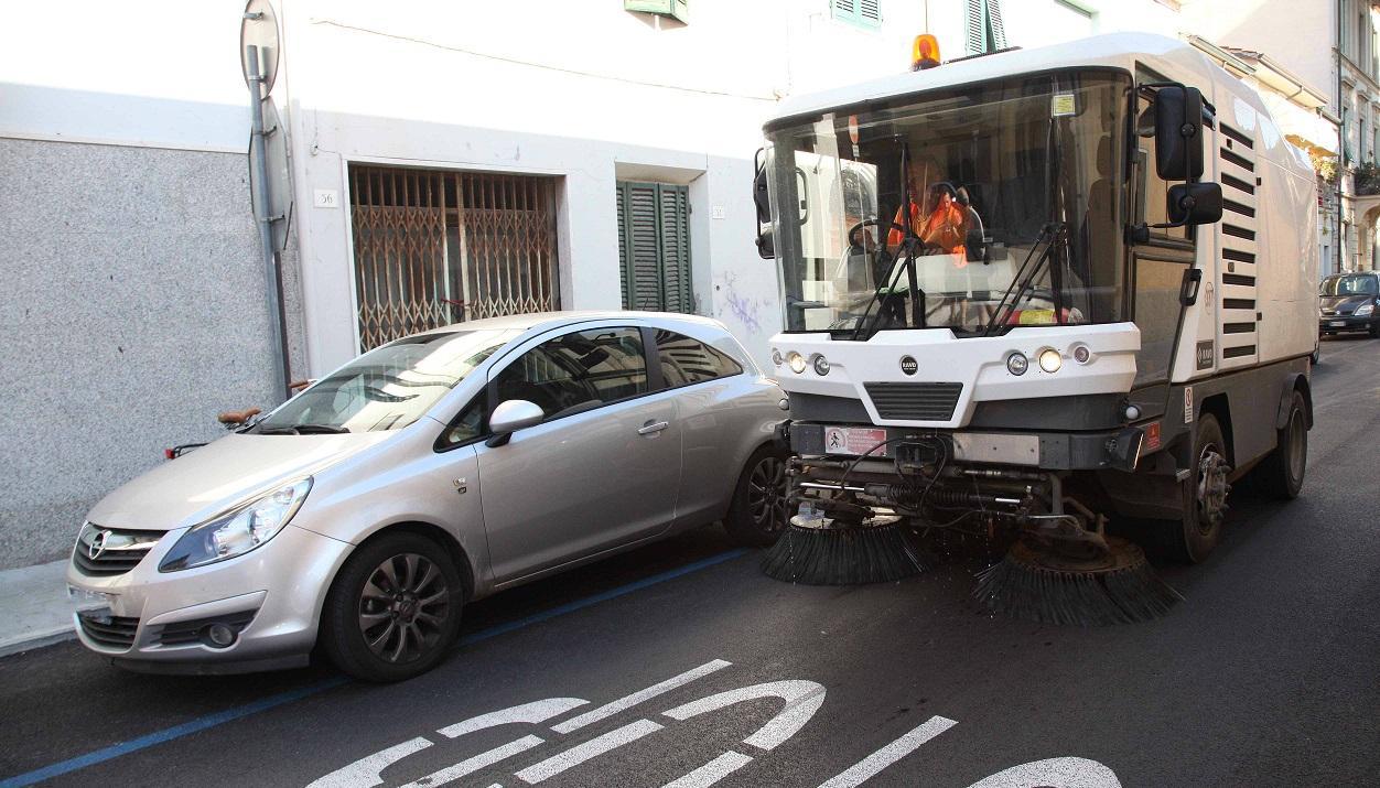 Una spazzatrice aggira un'auto lasciata in sosta vietata durante la pulizia della strada (foto d'archivio)