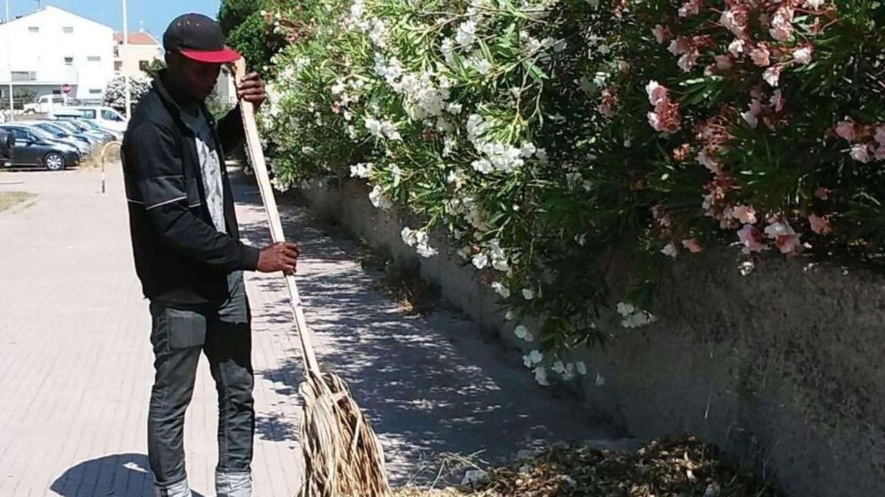 Il migrante che ripulisce la strada